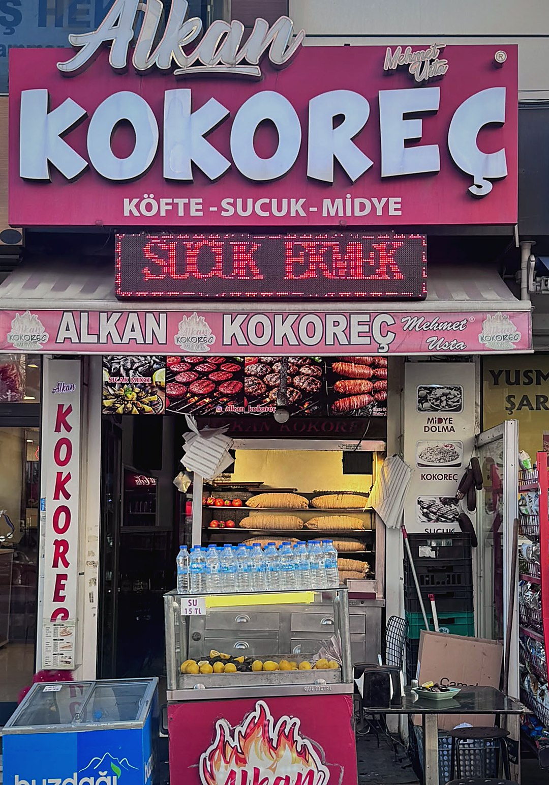 Alkan Kokoreç dükkanının tabelası ve camekanda şişte kokoreçler